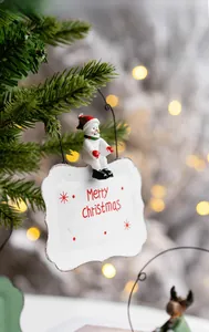 Close-up of metal snowman Christmas door hanger with Merry Christmas sign on tree