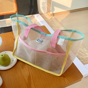 Close-up of mesh tote bag with colorful pink handles on a rustic wooden table
