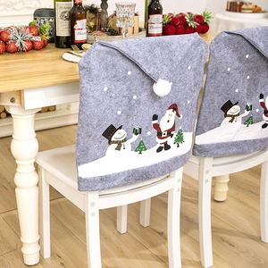 Close-up of gray felt Christmas chair covers with snowman and Santa motifs on white chairs