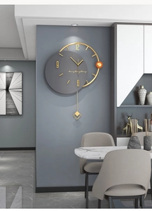 Close-up of minimalist wall clock with dark grey dial, gold frame, and pendulum detail