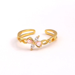 Gros plan d'une bague papillon avec zircons roses et blancs sur anneau doré