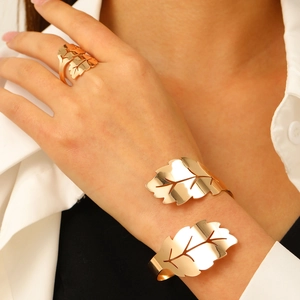 Detalle del conjunto de anillo y brazalete dorado con forma de hoja y acabado metálico
