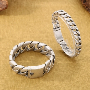 Close-up of vintage silver Cuban link chain bracelets with square clasp details