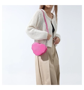 Detalle de bolso rosa con forma de corazón y patrón de telaraña en una modelo femenina