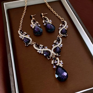 Dettaglio set gioielli in oro con gemme viola a goccia in una confezione da esposizione