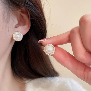 Elegant gold-plated pearl earrings worn by a model showcasing vintage jewelry design