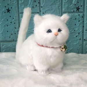 Realistic white plush toy cat with blue eyes, red collar and golden bell on a furry mat
