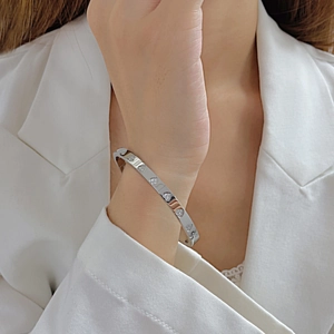 Close-up of a silver stainless steel heart-shaped diamond open bangle on a wrist