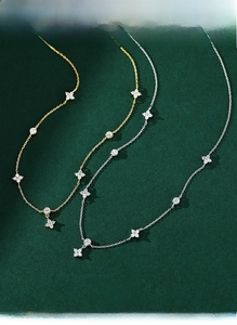 Close-up of S925 silver clover necklace with zircon detailing on dark green backdrop