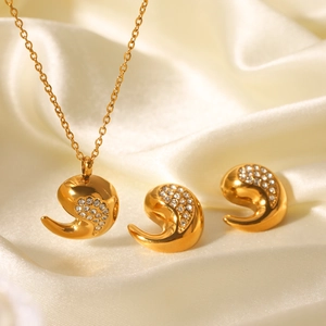 Parure de bijoux dorés en forme de goutte avec zircons sur fond de soie beige