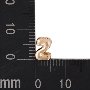 Detail view of a 7mm golden metal number 2 bead with ruler to show exact size