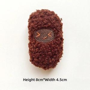 Detailed view of an 8cm brown plush food pendant with cute embroidered smiling face