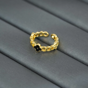 Macro detail of a golden chain-style open ring featuring a black clover floral design