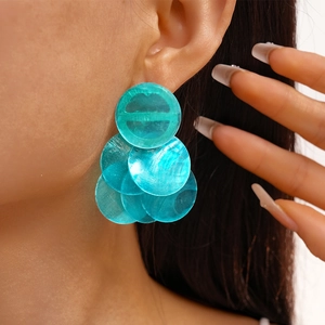 Close-up of a model wearing tiered turquoise round shell resin earrings in a boho style
