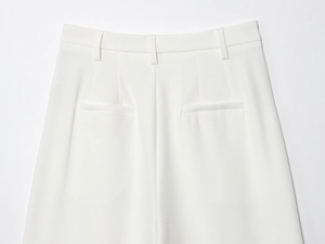 Détail d'un pantalon blanc avec des passants de ceinture et des poches passepoilées