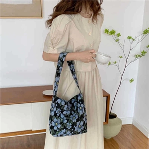 Lifestyle shot of large hobo shoulder bag with blue floral pattern on black canvas