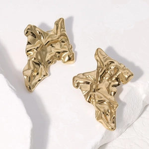Macro detail of gold irregular wrinkled geometric earrings with polished metal texture