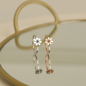 Anelli a margherita minimalisti in argento e oro rosa su un vassoio a specchio decorativo