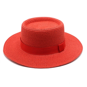 Detail view of woven red boater hat texture with matching ribbon and flat brim