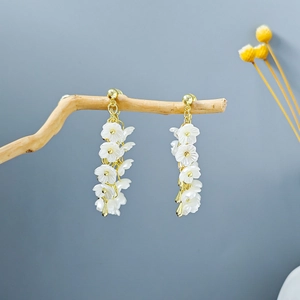 Detail of long floral tassel earrings with white blossoms on a wooden branch
