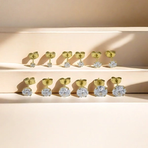 Golden titanium steel stud earrings with white zircon in graduated sizes on beige steps