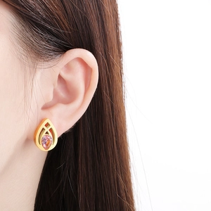 Elegante goldene Edelstahl-Ohrringe in Tropfenform mit rosa Kristall am Model getragen