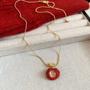Detailed view of apple pendant necklace with gold ball chain and red zircon resin