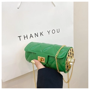 Detail of green cylinder bag with quilted pattern, gold chain and pearl side accents