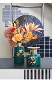 Detail of green ceramic vases featuring golden ginkgo leaf relief and gilded rim accents