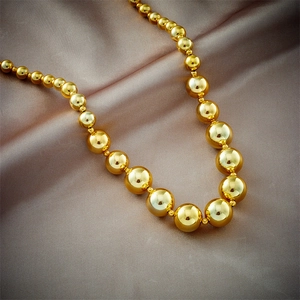 Polished gold beaded necklace with gradient sphere sizes on elegant silk fabric
