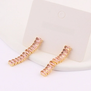 Detail of elegant gold earrings with rectangular pink crystals and micro-set zircons