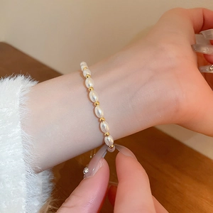 Elegant pearl bracelet with gold beads shown on a wrist with a soft white sweater cuff