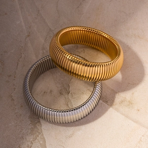 Nahaufnahme flexibler gold- und silberfarbener Schlangenketten-Armreifen mit Hochglanz-Finish