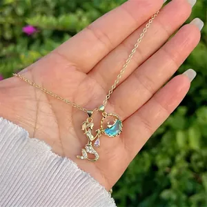 Close-up of gold mermaid pendant with blue gemstone and sparkling zircons on fine chain