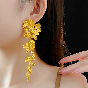 Détail de longues boucles d'oreilles dorées à fleurs et vignes portées par un mannequin