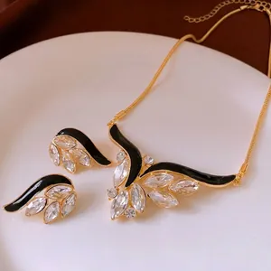 Vintage gold wing jewelry set with black enamel and marquise crystals on a ceramic tray