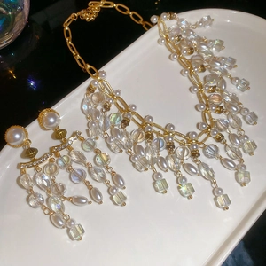 Macro shot of pearl and crystal tassel jewelry set on a white ceramic tray