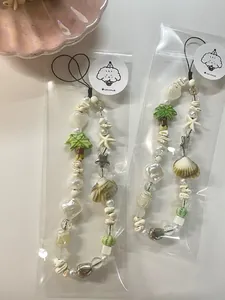 Detail of beach-themed phone charms with shells, pearls, and starfish beads