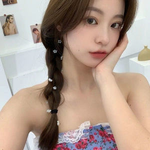 Dettaglio della clip per capelli a fiore bianco con nappina su treccia per stile estivo