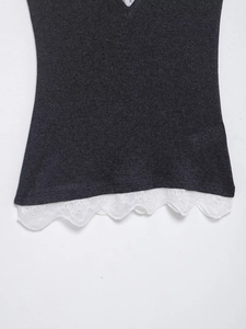Détail du haut en tricot gris foncé avec bordure délicate en dentelle fleurie blanche