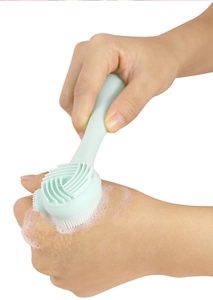Detail of light green dual-sided silicone facial brush with soft bristles and massage texture