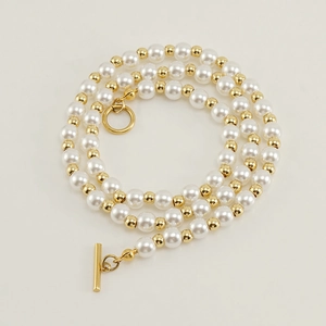 Detail view of pearl and gold bead chain necklace featuring a modern toggle clasp