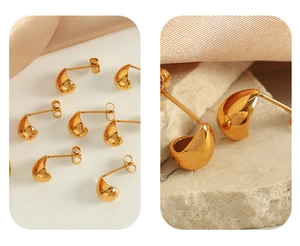 Macro shot of polished gold water drop stud earrings on textured stone and beige silk
