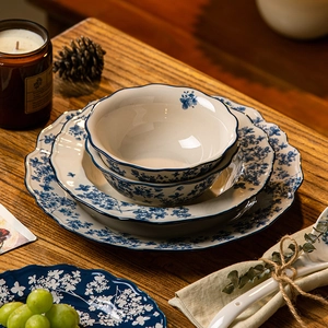 Blue and white ceramic dinnerware set with floral patterns on a rustic wooden table