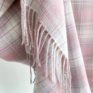 Close-up of soft pink and white plaid scarf fabric with elegant fringe detailing