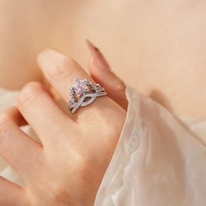 Close-up of a silver ring with a pink star zircon and diamonds on a model's finger