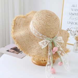 Detail of handmade straw hat with floral lace trim and pink tulip pendants decoration