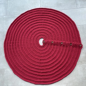 Close-up of red knitted Christmas tree skirt with wooden buttons and textured knit pattern
