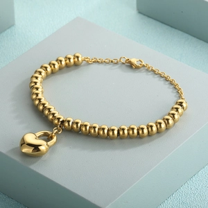 Detailed shot of gold-plated beaded bracelet with polished heart lock pendant