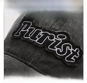 Macro view of distressed washed cotton fabric with Purist letter embroidery on cap